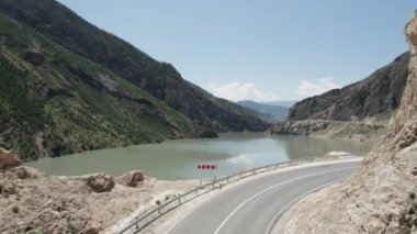 Güzel bir yaz kuşbakışı bakış açısı. Motor. Denizin karşısındaki büyük yeşil dağların güzel manzarası, yanında arabalar için bir yol ve mavi bir gökyüzü var..