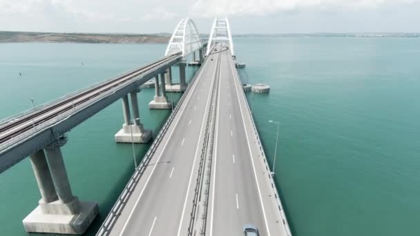 Vue aérienne le long du long beau pont au-dessus de la mer turquoise. L'action. Voler au-dessus du pont de flexion avec des voitures de conduite. — Video