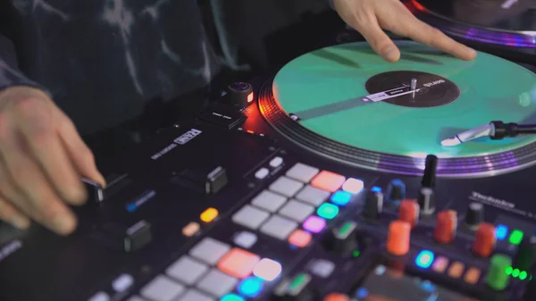 DJ točí rekord na diskotéce. Umění. Detailní záběr DJovy ruky na mixéru. Zářící hudební panel na párty. Hudebníci pracují v nočním klubu — Stock fotografie