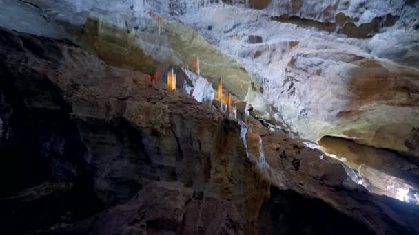 Uvnitř osvětlené jeskyně. Akce. Úžasná příroda kamenných jeskyní uvnitř hor. Výlety do jeskynních muzeí. Sloupy z přírodního kamene v jeskyni — Stock video