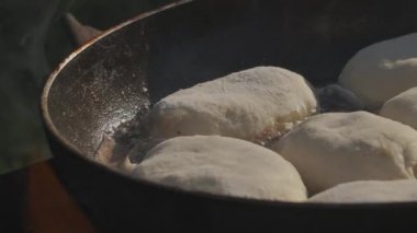 Tavadaki turtalar. Yaratıcı. Hamur sıcak tavada kızarıyor. Yağ kaynıyor. Doğada açık ateşte yiyecek kızartmak.
