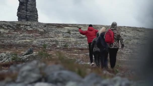 Eine Gruppe von Freunden wandert in den Bergen. Clip. Menschen gehen zwischen Steinsäulen hin und her. Wandern bei trübem Wetter in den Bergen — Stockvideo