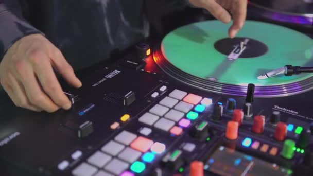 DJ točí rekord na diskotéce. Umění. Detailní záběr DJovy ruky na mixéru. Zářící hudební panel na párty. Hudebníci pracují v nočním klubu — Stock video