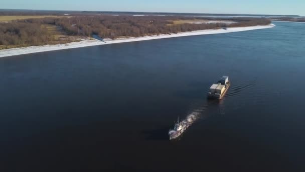 Aerial view of a barge floating on a wide river past the autumn meadows. Clip. The cargo ship carrying goods at a navigable river. — Stock Video