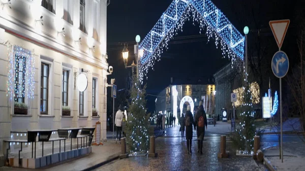 Praça da cidade lindamente decorada para o Ano Novo e Natal. Acção. Caminhando pessoas e turistas nas ruas decoradas e praças da cidade noturna. — Fotografia de Stock