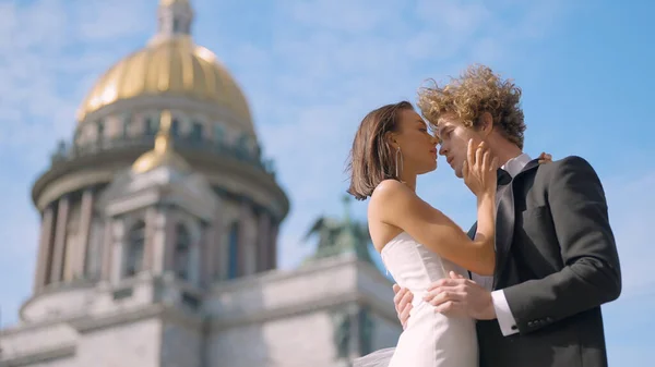 Wedding photo shoot. Action. A couple poses next to St. Isaac s Cathedral , a young man with long curly hair and his bride with bare shoulders and long earrings — 图库照片