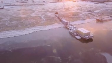Kışın deniz gemisinin boşaltılma görüntüsü. Şarjör. Kış sabahı kıyıya indirilen deniz gemisinin güzel manzarası. Tüccar gemisi şafak vakti karlı kıyıya indirildi.