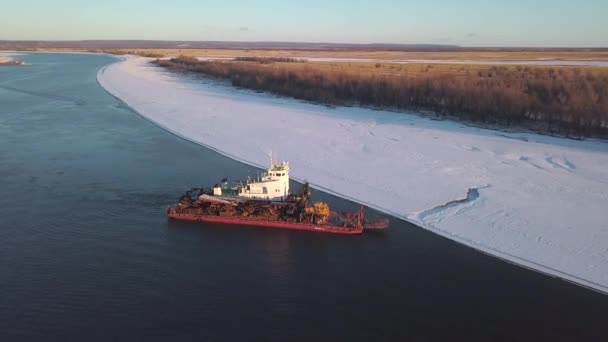 Ένα πλοίο που μεταφέρει φορτίο. Κλιπ. Πλοία που πλέουν σε ένα ποτάμι που λιώνει την άνοιξη με ένα μεγάλο φορτίο στο φόντο των δασών με χιόνι γύρω και γαλάζιο ουρανό από πάνω. — Αρχείο Βίντεο