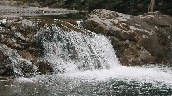 美丽的瀑布落在山区的河边.创意。平静的小瀑布和冰冷的流水. — 图库照片