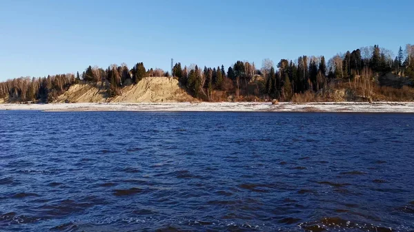 有河流的风景。剪断。一条冰封的泉水，你可以看到结冰的森林和草地，还有明亮的清晨的天空. — 图库照片