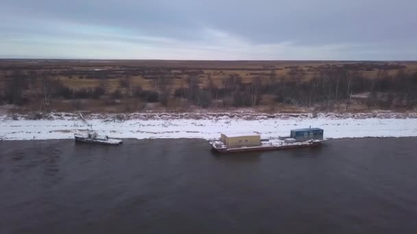 Pohled z helikoptéry. Jarní krajina, kde velké lodě vyvážejí náklad podél řeky vedle nahé mírně zasněžené lesy. — Stock video