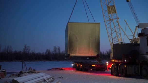 Prozess des Entladens eines Lastwagens mit einem Kran und Metallkabeln am Abend. Clip. Lastwagencontainer entladen. — Stockvideo