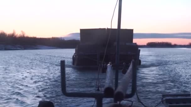 Μέρη ενός φορτηγού πλοίου. Κλίμακα.Ένα μεγάλο πλοίο με ρυμουλκούμενο που κινείται αναπτυσσόμενα κύματα στο ποτάμι και μεταφέρει φορτίο σε ένα σκοτεινό βράδυ με ένα όμορφο ηλιοβασίλεμα και ένα μωβ φόντο. — Αρχείο Βίντεο