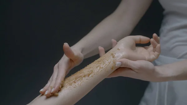在女性病人的手臂上涂上一层糖霜,这是护理身体的概念.行动。美容院美容过程中女性美容师手的近视. — 图库照片