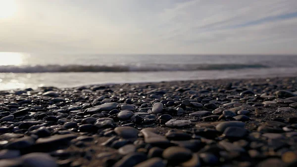 小卵石和海浪的卵石海滩。行动。海面上的野生鹅卵石沙滩上，平静的夜晚在干旱的海岸上. — 图库照片