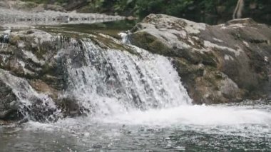 Ormandaki nehrin güzel doğal şelalesi. Yaratıcı. Nehir akıntısı şelaleye döner ve akmaya devam eder. Nehrin taştan manzarası şelale oluşturur.