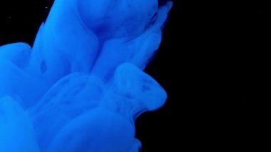 Üzerinde parlak mavi boyanın bulanıklaştığı siyah bir arkaplan. Stok görüntüleri. Siyah bir arka plandaki duman sanki tüm görüntülere nüfuz ediyor ve yayılıyor..