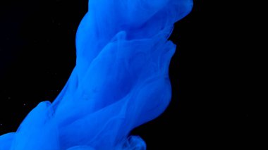 Mavi mürekkep siyah arka planda suyun altına düşer. Stok görüntüleri. Su altında akan güzel mavi boyaya yakın..