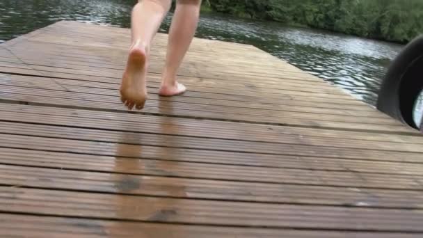 男が走って堤防から水の中に飛び込む。創造的だ。男はゆっくりと池へ泳ぎに行く。短い男が走って川の水の中に落ちる — ストック動画