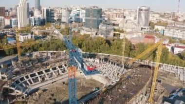 İnşaat eşyaları. Stok görüntüleri. İnsansız hava aracının görüntüsü. İnşaat alanının yanında güzel bir yaz şehri. Tüm ekipmanlarla birlikte. Mavi gökyüzündeki tüm binaları görebilirsiniz..