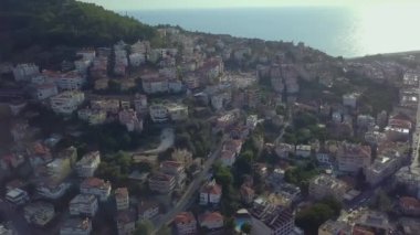 Quadcopter şehrin üzerinde uçuyor. Çıt. Deniz kıyısındaki dağlık bir bölgede şehrin kuş bakışı görüntüsü.
