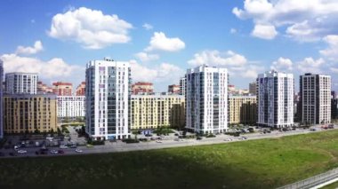 Güneşli bir yaz gününde modern bir şehir caddesinin havadan görünüşü. Stok görüntüleri. Mavi bulutlu gökyüzü arka planında modern bir uyku alanının binaları.