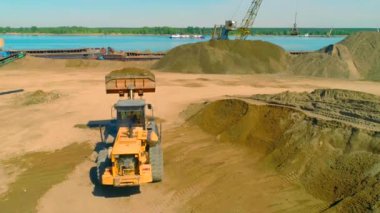 Bina manzarası. Yukarıdan bak. Nehrin yanındaki boş bir alanda büyük arabaların bir şeyler sürdüğü, inşa ettiği ve kargo taşıdığı bir orman var. .