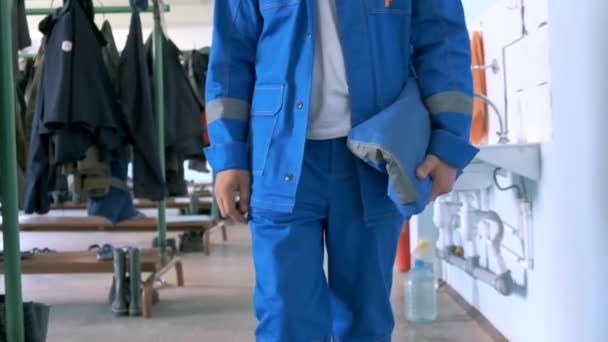Pracuj v továrně. Klip. Muž v modrém obleku a bílé helmě se snaží otevřít speciální elektrické zařízení pro práci. — Stock video