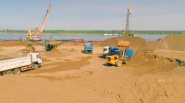 Bina manzarası. Yukarıdan bak. Nehrin yanındaki boş bir alanda büyük arabaların bir şeyler sürdüğü, inşa ettiği ve kargo taşıdığı bir orman var. .