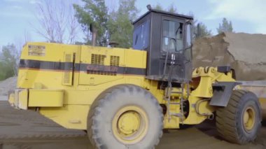 FRANCE, PARIS - 21 Mart 2022: bir kazıcı bir taş ocağından kum kaldırır. Sahne. Kazıcının yanında bir KAMAZ var. Kum bir taş ocağında mayınlanır. Arka planda taş ocağında bir göl var.