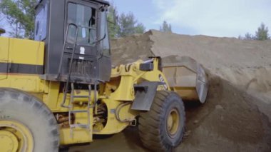 İngiltere, Londra - 21 Mart 2022: Bir kazıcı bir taş ocağından kum kaldırır. Sahne. Kazıcının yanında bir KAMAZ var. Kum bir taş ocağında mayınlanır. Arka planda taş ocağında bir göl var.