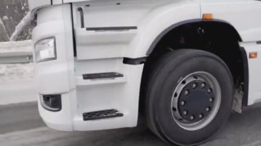 Rusya, MOSCOW - 21 Mart 2022: büyük beyaz bir kamyon yol boyunca ilerliyor. Sahne. Siyah tekerlekler Kamaz 'a yakın çekim. Beyaz kamyon kışın yola çıkar. Çerçevede bir sürü kamyon tekerleği var.