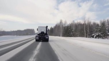 Rusya, MOSCOW - 21 Mart 2022: karlı bir yolda beyaz bir kamyon ilerliyor. Sahne. Büyük beyaz bir KAMAZ otoyol boyunca sürüyor. Ormanda arabaların gittiği bir yol var.