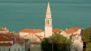 Kilise ve deniz dalgaları arka planında kulesi olan eski bir kasabanın zamanaşımı etkisi. Yaratıcı. Güzel doğa ve mimari.