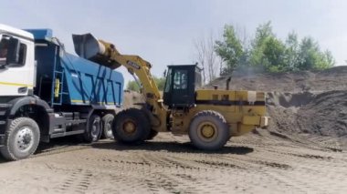 Yekaterinburg, Rusya - Ağustos 2021: İnşaat süreci. Sahne. Büyük kamyonlar şehrin yanındaki düz arazide bir şey sürüp inşa ediyorlar..