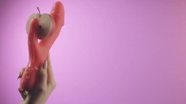 Pembe arka plan. Yaratıcı. Vibratör, el ele tutuştu. Parlak kırmızı bir elma koydular ve sümüksü beyaz kremayla doldurdular..