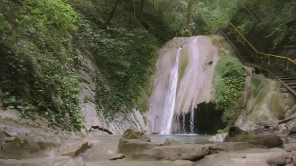 Escaleras turísticas junto a una pequeña cascada en el bosque. Creativo. Una hermosa ruta para los turistas pasa por un río con una cascada — Vídeo de stock