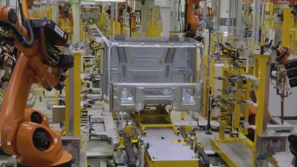 모스크바 러시아, 01.14.2022 : 공장에서 로봇이 차를 조립합니다. 스카인. 공장에서 흰색 자동차는 오렌지색 로봇 팔로 조립됩니다. 차와 트럭은 제조소에 조립됩니다 — 비디오