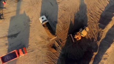 Kuş bakışı görüş. Sahne. Boş bir çöl arazisindeki büyük kamyonlar inşaat işi üretiyor..