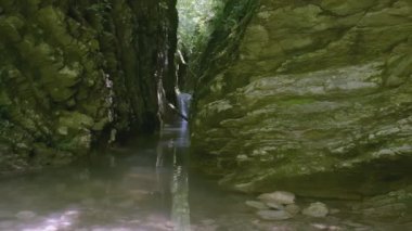 Küçük bir dağ nehri, sonunda bir şelalenin görüldüğü bir geçitten akar. - Yaratıcı. Turist yolu küçük bir şelalenin yanından geçiyor.
