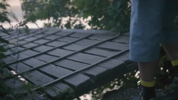 The childs feet step on the bridge. CREATIVE. The boy is walking across the bridge. A small child in blue sandals walks along a wooden bridge — Stock Video