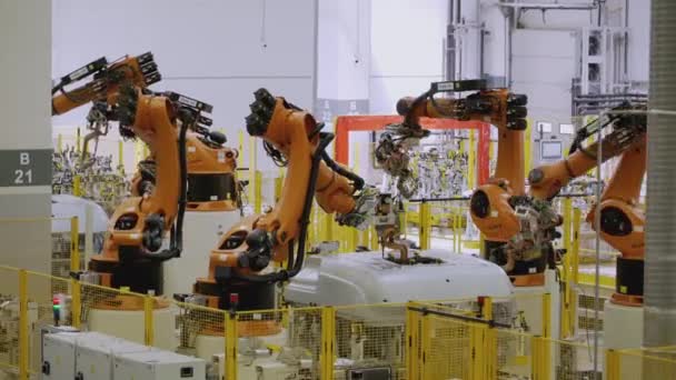Moscou - Rússia, 01.14.2022: Robôs na fábrica montam o carro. CENE. Na fábrica, um carro branco é montado por braços robóticos laranja. Carros e caminhões são montados no manufactory — Vídeo de Stock
