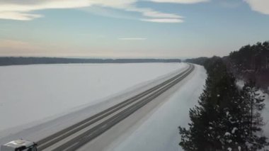 Arabaların ve kamyonların sürdüğü kış yolunun en üst manzarası. Sahne. Gökyüzü ve yeryüzü kardan mavidir. Araba pisti kar yığınlarının arasında yatıyor. Pistte yukarıdan kuadkopterden görüntüle