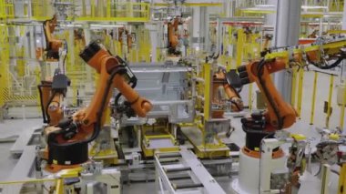 Moskova - Rusya, 01.14.2022: Fabrikadaki robotlar arabayı monte ediyor. Sahne. Fabrikada, turuncu robotik kollarla beyaz bir araba monte edilir. Arabalar ve kamyonlar fabrikada toplandı.