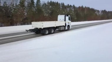 Arabaların ve kamyonların sürdüğü kış yolunun en üst manzarası. Sahne. Gökyüzü ve yeryüzü kardan mavidir. Araba pisti kar yığınlarının arasında yatıyor. Pistte yukarıdan kuadkopterden görüntüle