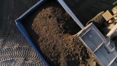 İnşaat süreci. Çimentoyla kaplı ve yükseklikten kaldırılan büyük makineler kargoyu boş bir alana yükleyip inşaat için boşaltıyor..