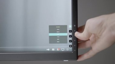El monitörü çalışacak şekilde ayarlar. Aksiyon. Siyah bir monitör bir adamın elini ayarlar. Ekranın altındaki ayarlara hafif bir el basar