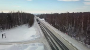 Arabaların ve kamyonların sürdüğü kış yolunun en üst manzarası. Sahne. Gökyüzü ve yeryüzü kardan mavidir. Araba pisti kar yığınlarının arasında yatıyor. Pistte yukarıdan kuadkopterden görüntüle