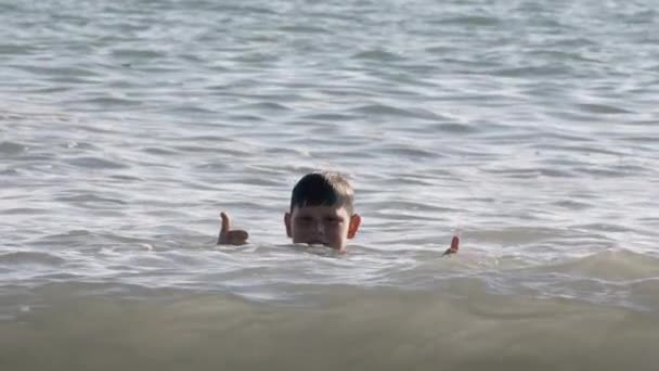 Siyah saçlı bir çocuk anne ve babasıyla birlikte denizde yüzüyor. - Yaratıcı. Çocuk kıyıda duran ailesine iyi iş çıkardığını gösterir. — Stok video
