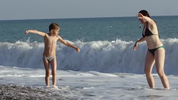 Mother and son come out of the sea with waves after swimming. CREATIVE. Family on summer vacation swimming at the sea — Stock Video